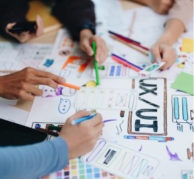 Table with UX/UI design paper and hands of people